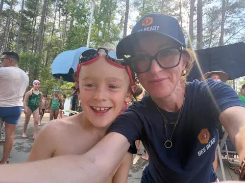 A BeeReady volunteer poolside with a young swimmer fresh out of the pool.