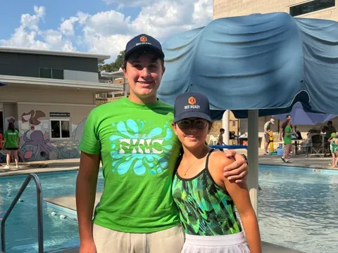 Two of our young BeeReady helpers in branded hats standing poolside.