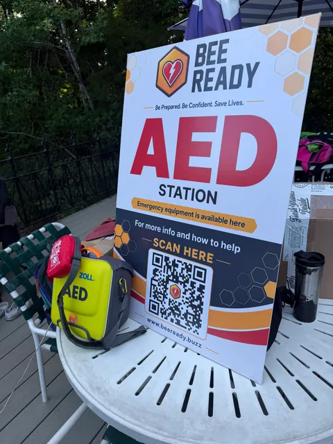 A Bee Ready AED station banner next to a ZOLL AED at the swim meet.