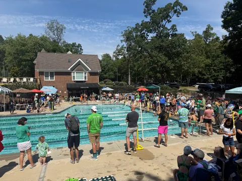 Swimmers and families gathered around the pool with the clubhouse behind them.