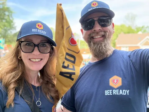 Bee Ready volunteers smiling next to the AED flag at the swim meet.